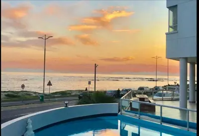 a swimming pool with a view of the ocean at Sunset Accommodation in Strand in Strand