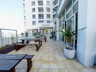 a patio with benches and tables on a building at Sunset Accommodation in Strand in Strand