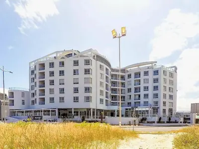 a white building with a flag on top of it at Sunset Accommodation in Strand in Strand