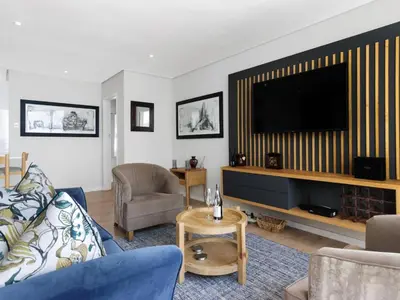 a living room with a couch and a flat screen tv at Sunsets on Beach Strand in Cape Town