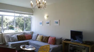 a living room with a couch and a tv at Ocean Elephant Beach Apartment LONG TERM in Strand