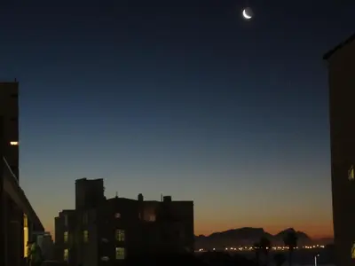 a view of a city at night with the moon at Ocean Elephant Beach Apartment LONG TERM in Strand