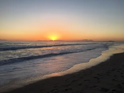 a sunset on a beach with the ocean at De Boerderij in Strand