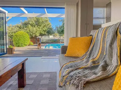 a couch sitting in a living room next to a pool at Chanteclair Re-Energised 1 Bed 1 Bath in Hermanus