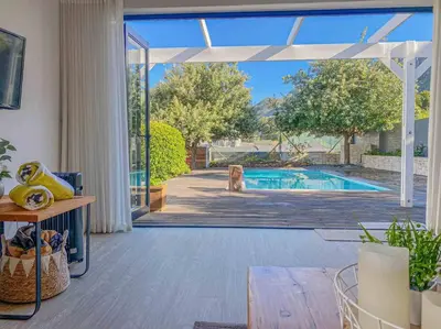 a living room with a door open to a swimming pool at Chanteclair Re-Energised 1 Bed 1 Bath in Hermanus