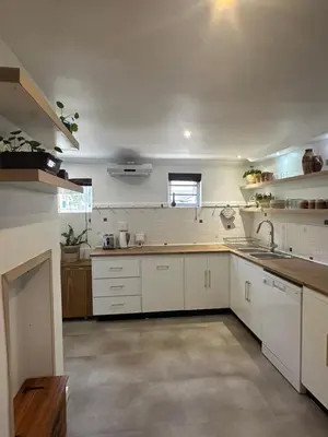a large kitchen with white cabinets and a sink at Koetshuis on High Street in Paarl