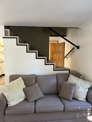 a living room with a couch and a staircase at Koetshuis on High Street in Paarl
