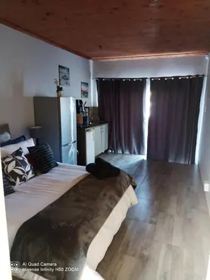 a bedroom with a large bed and a refrigerator at Jennings breeze in Cape Town