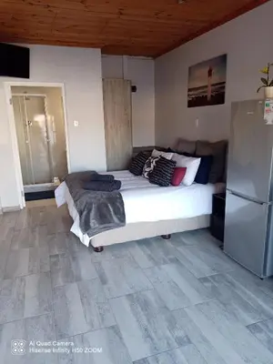 a bedroom with a large bed and a refrigerator at Jennings breeze in Cape Town