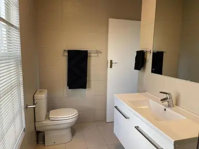 a white bathroom with a toilet and a sink at Paradyskloof home in Stellenbosch