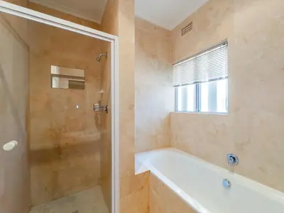 a bathroom with a tub and a shower with a glass door at Paradyskloof home in Stellenbosch