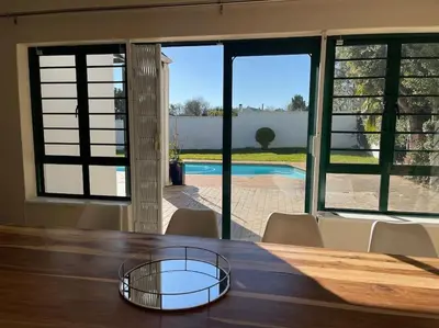 a dining room table with a view of a pool at Paradyskloof home in Stellenbosch