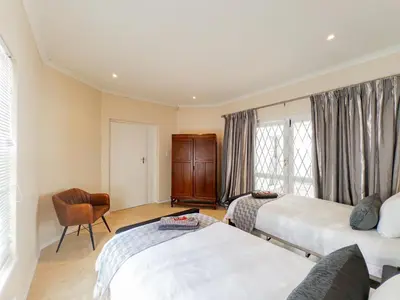 a bedroom with two beds and a chair and a window at Paradyskloof home in Stellenbosch