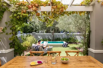 a garden with a pergola and a wooden table at Lush garden 3 bedroom house in Franschhoek