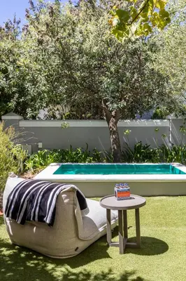a couch and a table next to a pool at Lush garden 3 bedroom house in Franschhoek