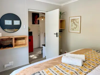 a bedroom with a large bed and a hallway at Amsterdam Suite in Cape Town