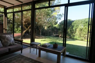 a living room with a couch and a large window at Hidden gem in bush 350m from main beach in Bettyʼs Bay