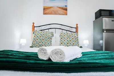 a bed with green sheets and towels on it at Modern & Central 1 BR Apt Close To Major Attractions in Cape Town