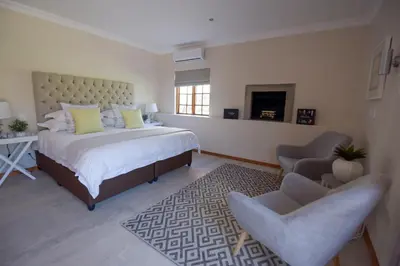 a bedroom with a bed and two chairs and a fireplace at Cultivar Boutique Hotel in Stellenbosch