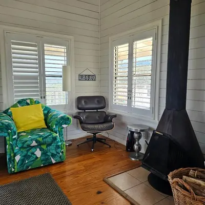 a living room with a fireplace and a chair at MAGNIFICENT 6 sleeper mountain getaway in Romansrivier