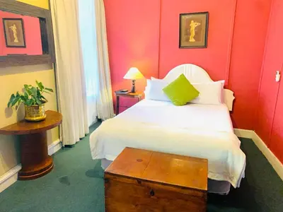 a bedroom with a white bed and red walls at Mill House Bed and Breakfast in Stellenbosch