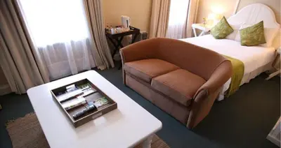 a hotel room with a bed and a couch and a table at Mill House Bed and Breakfast in Stellenbosch