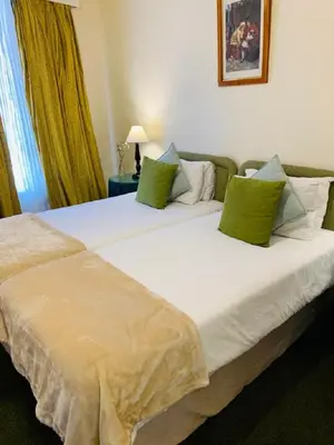 a large white bed with green pillows in a room at Mill House Bed and Breakfast in Stellenbosch