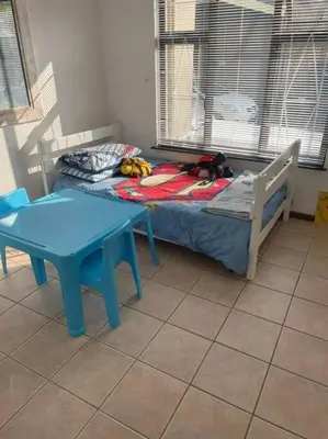 a bed and a table in a room with a blue table at Somerset West Family home holiday rental in Cape Town