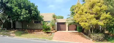a house with a garage in front of a street at Somerset West Family home holiday rental in Cape Town