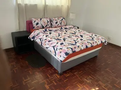 a bedroom with a bed with a floral comforter at House On Gill 3 in Cape Town