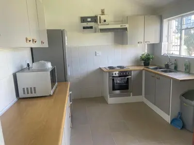a kitchen with white cabinets and a sink and a stove at House on Gill 25 in Cape Town