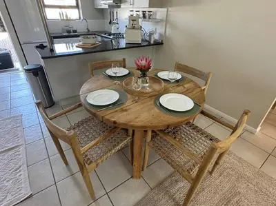 a wooden table with four chairs and a kitchen at Slaap Self Catering in Paarl