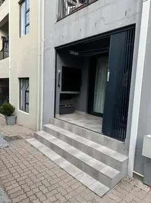 a building with stairs leading to a door with a television at Slaap Self Catering in Paarl