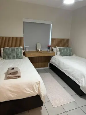 a bedroom with two beds and a blank screen at Slaap Self Catering in Paarl