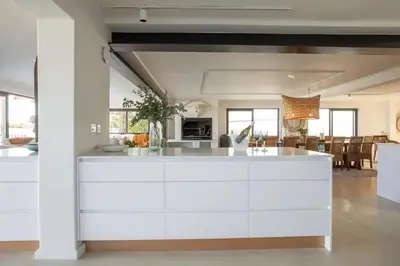 a kitchen with white cabinets and a living room at Les Baleines Hermanus Villa in Hermanus