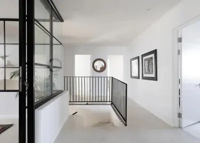 a hallway with white walls and a black and white staircase at Les Baleines Hermanus Villa in Hermanus