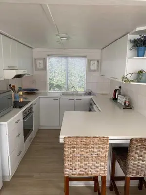 a kitchen with white cabinets and a table and chairs at Moonshine in Hermanus