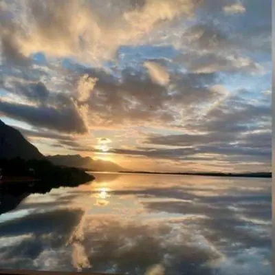 a sunset over a body of water with a cloudy sky at Moonshine in Hermanus