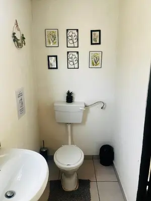 a bathroom with a toilet and a sink and pictures on the wall at Relaxa Sleep & Go - Self Catering Accommodation in Cape Town