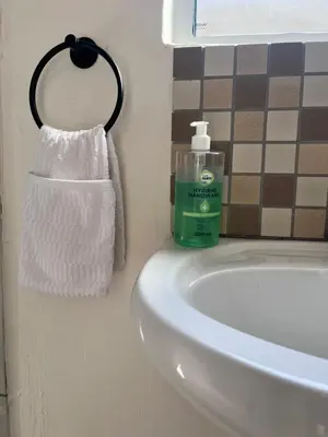a bathroom sink with a bottle of soap and a towel at Relaxa Sleep & Go - Self Catering Accommodation in Cape Town