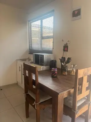 a dining room table with two chairs and a microwave at Relaxa Sleep & Go - Self Catering Accommodation in Cape Town