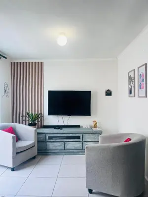 a living room with a television and two chairs at Relaxa Sleep & Go - Self Catering Accommodation in Cape Town