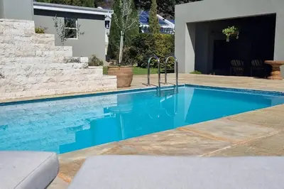 a swimming pool with blue water in front of a house at C'est la Vie 2 in Franschhoek