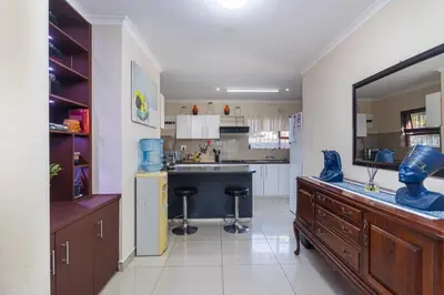 a kitchen with a counter and stools in it at Ina se Huisie in Blouberg self Catering Apartment in Cape Town