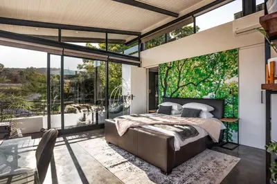 a bedroom with a bed and large windows at In-a-Tree in Paarl