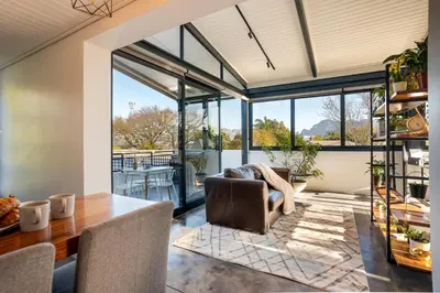 a dining room with a table and chairs and windows at In-a-Tree in Paarl