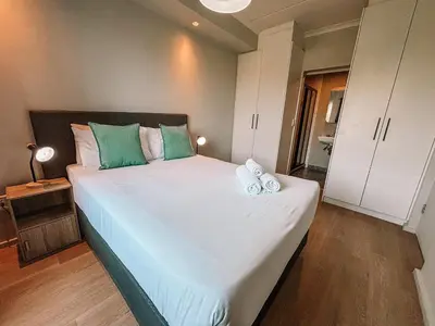 a bedroom with a large bed with green and white pillows at Cape Mae Apartment Hotel in Cape Town