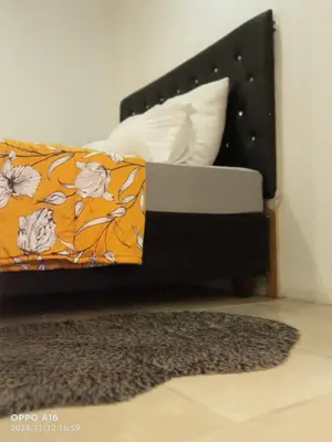 a bed with an orange and white pillow and a rug at KK Guesthouse in Cape Town