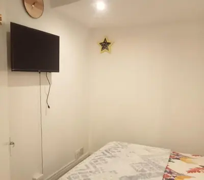a bedroom with a bed and a tv on the wall at KK Guesthouse in Cape Town