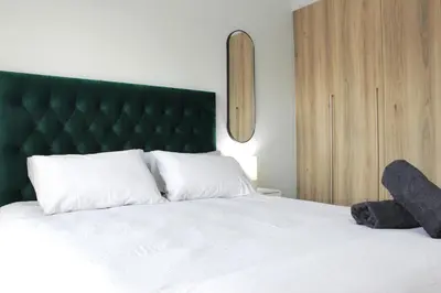 a bedroom with a white bed with a green headboard at The Jade Escape in Cape Town